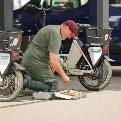 Mitarbeiter repariert Lastenräder bei Betriebstour 